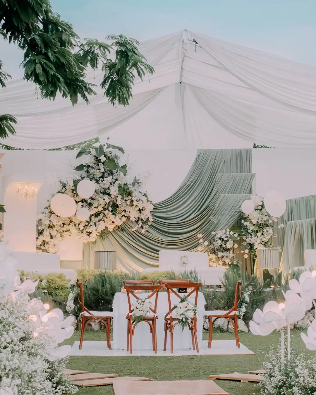 A white and sage draped altar dressed with flowers on the lawn