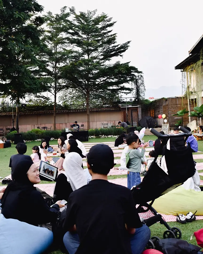 Families picnicking on the grass with children playing nearby