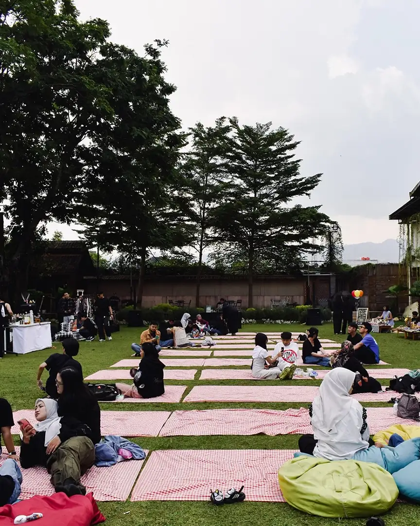 Picnic mats spread across the wide lawn with guests sitting in groups