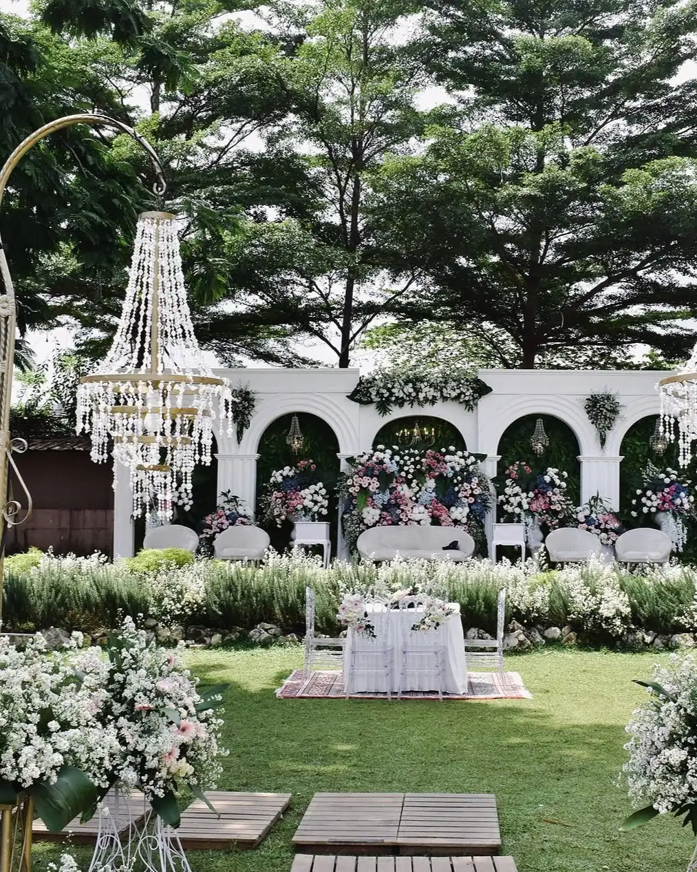 Wedding decor with chandeliers and white arches on the lawn